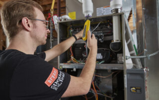 A Weather Changers employee working on a furnace heating system in the Denver metro area.