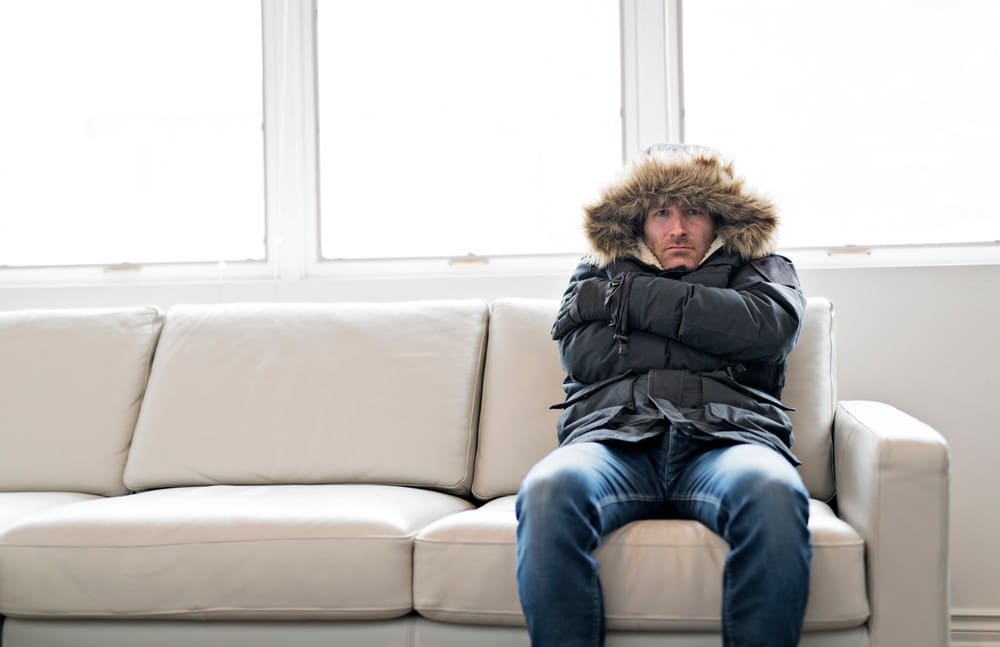 Man with warm clothing freezing inside the house