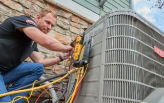 Technician using diagnostic tools and gauges on an outdoor air conditioning unit.