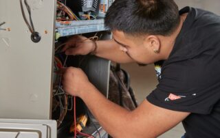A Weather Changers technician working on a furnace in Denver, CO.