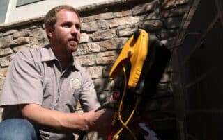 An employee wearing a Weather Changers shirt and working outside on a ac unit.