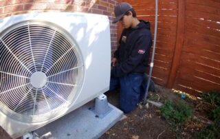 HVAC technician working on a heat pump system outside.