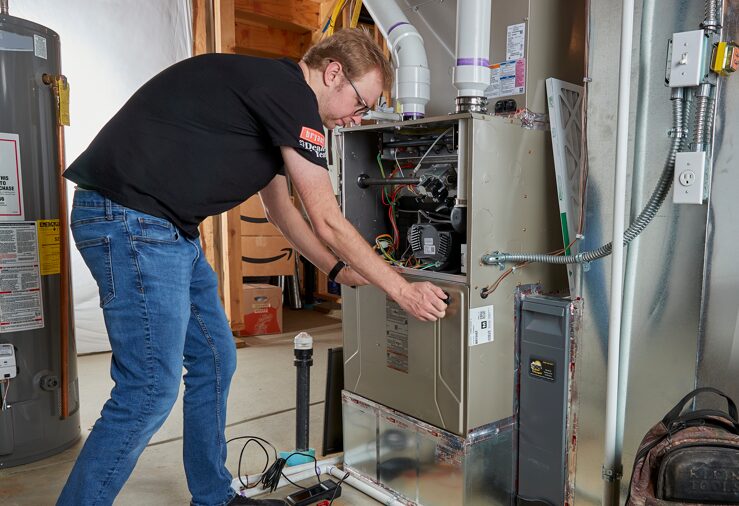 A Weather Changers technician working on a furnace heating system in Denver, CO.